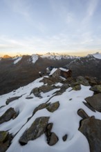 Snow-covered mountain landscape, mountain hut Ramolhaus in autumn with snow, at sunset, view of