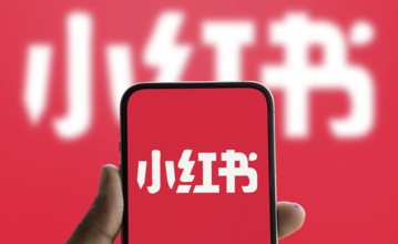 RedNote (Xiaohongshu) logo is displayed on smartphone
