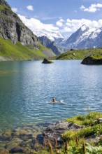 Woman bathing in mountain lake Lac de Louvie, behind summit of Grand Combin, Val de Bagnes, Valais,