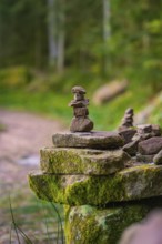 Balanced stone towers on a moss-covered stone along a forest path, Glaswaldsee, Bad