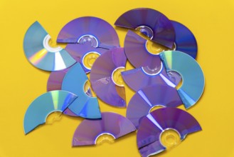 Top view of cut CDs and DVDs against a yellow background