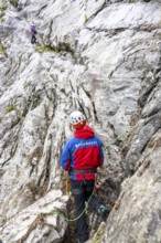 Mountain rescuers from Bergwacht Bayern climbing a steep rock face on Hoher Göll, Berchtesgaden,