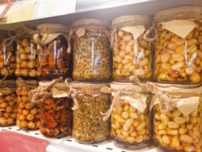Jars of honey filled, with various nuts and seeds, are displayed on the store shelf, no people,