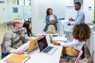 Diverse marketing team analyzing growth charts during a productive meeting in a modern coworking