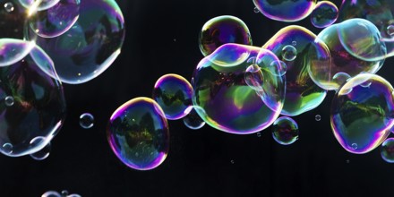 Iridescent soap bubbles in the colours of the rainbow against a black background, Recklinghausen,