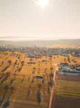 Extensive fields and trees with village in the background, in a misty autumn landscape, Neubulach,