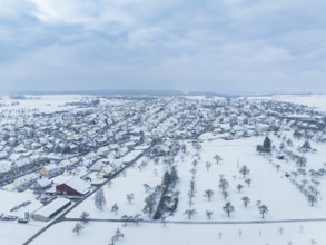 Snow-covered village with surrounding fields under a cloudy sky, Deckenpfronn, Böblingen district,