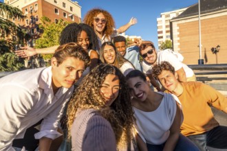 Frontal view of a multi-ethic cheerful friends taking selfie together in the city