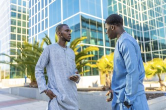 Two senegalese businessmen wearing traditional dashiki attire are discussing business in front of