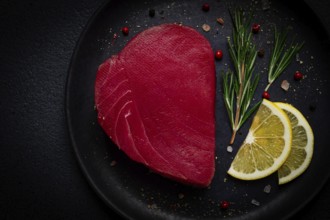 Fresh red tuna fillet, for steak, raw, top view, on a black plate, no people