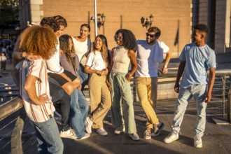 Relaxed group of friends talking standing in the city during sunset