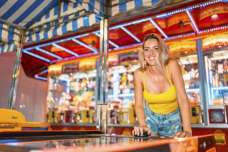 Blonde caucasian smiling woman playing arcade games at night in an amusement park