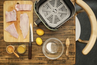 Fish fillets are arranged on a cutting board next to a bowl and spices. Fresh lemons rest nearby,