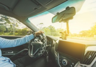 Interior view of a man driving a car. Driver hands on the steering wheel