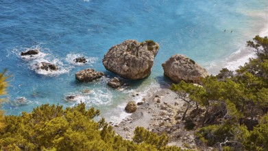 Large rocks in the turquoise sea on a coast overgrown with pine trees, Kato Lakkos Beach, still
