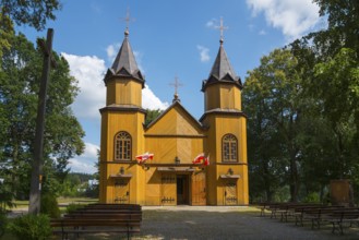 Wooden church with two towers, surrounded by trees and under a blue sky in the sunshine, wooden