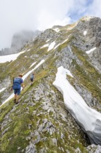 Two mountaineers with helmets on a narrow hiking trail, ascent to the Ackerlspitze, clouds moving