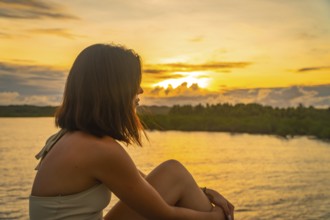 Young woman enjoying a peaceful golden sunset over the tropical landscape of siargao island,