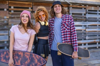Group of cheerful friends enjoying time at skateboarding park. Female and male skaters standing
