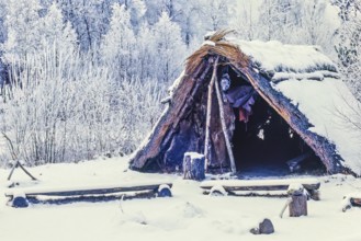 Reconstruction of a Stone Age settlement with a grass hut with snow and frost a cold winter day,