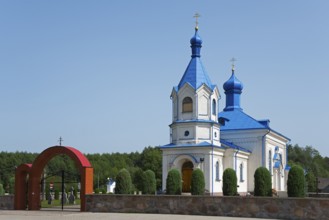 Orthodox church with blue roof and magnificent archway, surrounded by green landscape, Orthodox