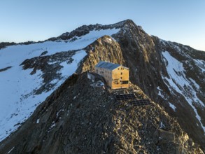 Atmospheric sunrise in a picturesque mountain landscape, alpenglow, aerial view, mountain hut