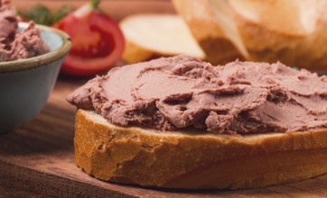 Liver meat pate spread, on white bread, on a wooden background, breakfast, close-up, no people,
