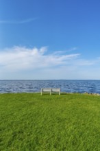 Isolated, white, empty bench in a meadow on the shore of the Szczecin Lagoon in the village of