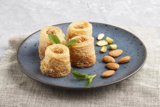 Kunafa, traditional arabic sweets in blue ceramic plate on a gray concrete background. side view,