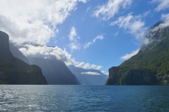 Majestic fjord with dominant mountains and few clouds under a blue sky, summer, Milford Sound, Te