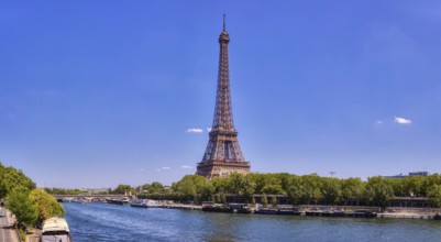 The Eiffel Tower from afar with a river and green treetops on a sunny day, Paris