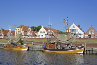 Crab cutter in the harbour in front of historic buildings, blue sky, Greetsiel, North Sea, Lower
