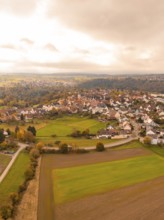 View of a village with autumnal fields and clouds, Tiefenbronn, Germany