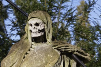 Grim Reaper, allegory of death with hourglass and scythe, sculpture at the Melaten Cemetery,