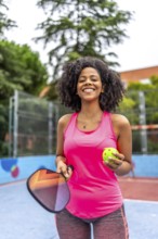 Vertical portrait of a latin female pickelball player standing smiling at camera in an outdoor