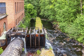 Old hydroelectric plant in a small river with a water tube in wood and a brick building, Ryfors,