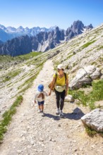 Tourists enjoying a summer hike on a mountain path in the italian alps, with breathtaking views of