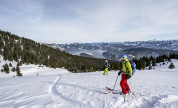 Two skiers skiing down the Simetsberg, view of Walchensee and mountain panorama, Estergebirge,