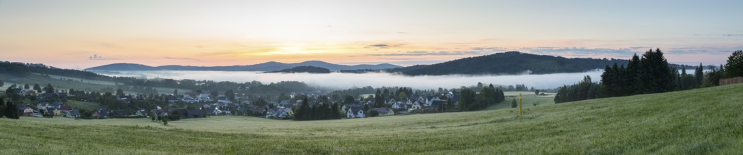 Panorama of the village view with the church of St. Mary's Assumption in the morning fog in front