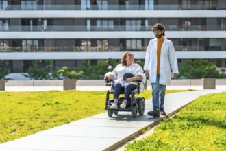 Doctor assisting a female patient in an electric wheelchair, strolling through a sunny park near