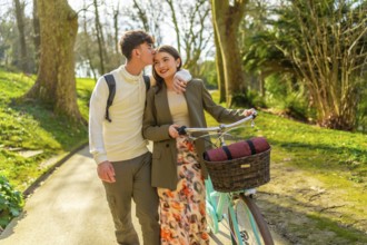 Young couple walking through park with bicycle, enjoying romantic moment together on sunny day