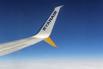 Wing tip of Rynair plane in flight against blue sky