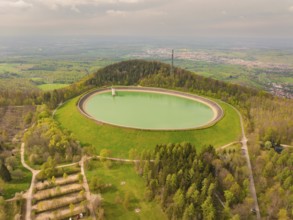 Upper reservoir hill with reservoir and forest, observation tower in the background under cloudy