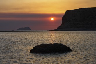 Sunset, sun next to cliff, rocks in the sea, Pontikos Island, orange sky, grey clouds, Gramvoussa