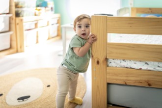 Full length portrait of a male baby taking its first steps in a room
