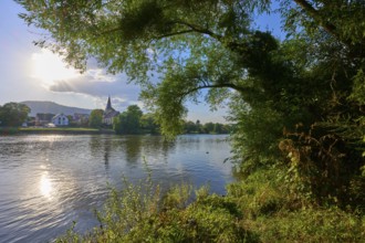 Idyllic river landscape with church in the background and lush vegetation on the banks, autumn,