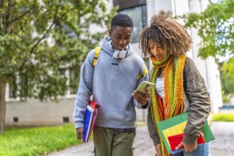 Multiracial college student walking out of class while looking at mobile phone