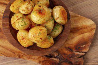 Baked new potatoes, with butter and dill, on a wooden plate, homely, rustic, no people