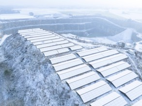 Snow-covered solar panels on hill in winter landscape with light fog, Nagold, Black Forest, Germany