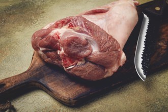 Raw pork knuckle, on a wooden chopping board, close-up, top view, no people